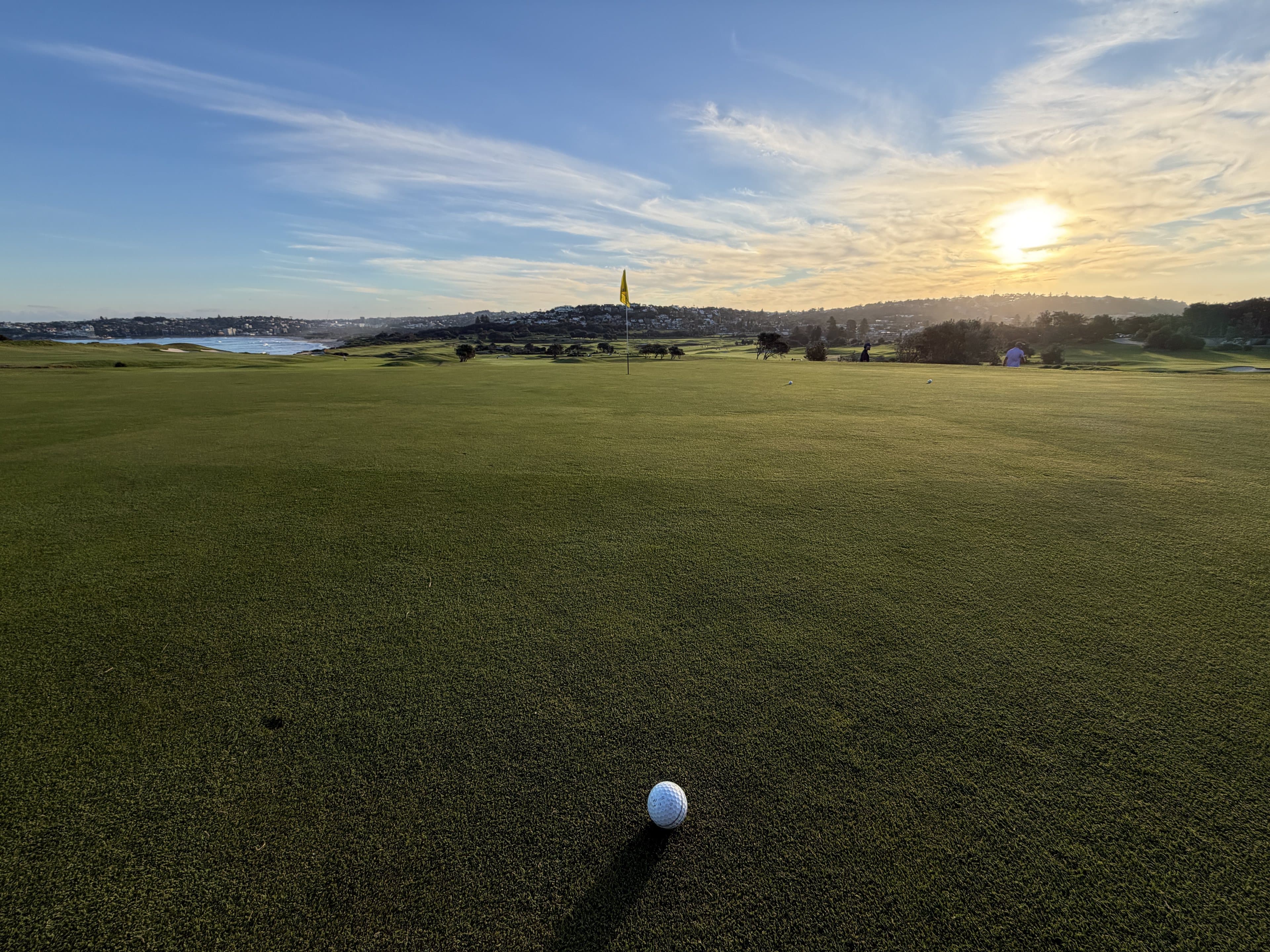 The fairway at Long Reef at sunset, a ball sitting up in the foreground and the flag ahead